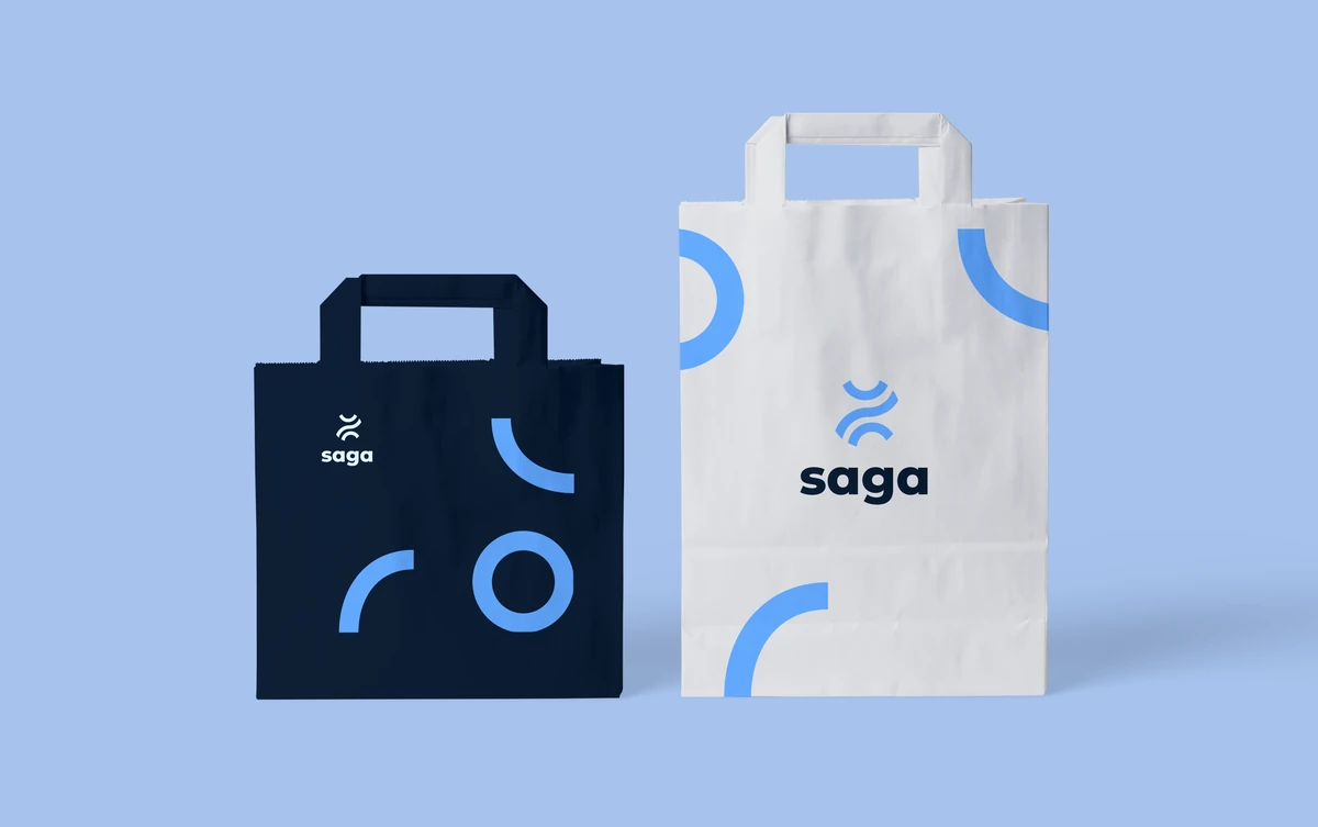 SAGA brand identity on two paper bags, one dark blue and one white